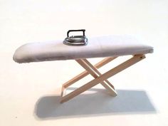 a miniature ironing board with an iron on it's side and a tea kettle sitting on top