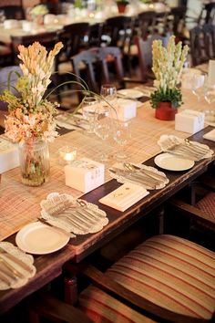 a long table with place settings and flowers in vases