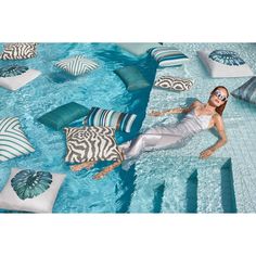 a woman laying on top of a blue pool surrounded by pillows and zebra print cushions