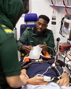 a man in a hospital bed with an oxygen tube hooked up to his chest and another person standing next to him