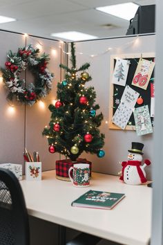 an office cubicle decorated for christmas with a small tree and decorations on the desk