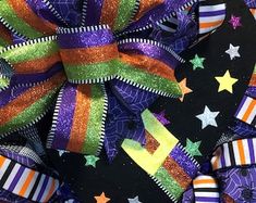 a purple, orange and green halloween wreath with stars on the front is featured against a black background