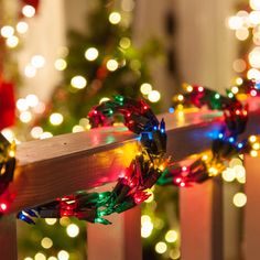 christmas lights are hanging on a wooden fence