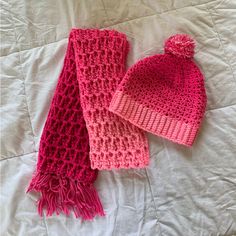 two knitted hats and scarfs laying on a bed