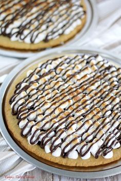 two cookies covered in chocolate and marshmallows sitting on top of a table