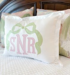 a close up of a pillow on a bed with decorative pillows and the letter snr