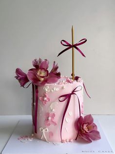 a pink cake decorated with flowers and a cross