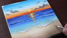 someone is painting a sunset at the beach with watercolors on canvase paper