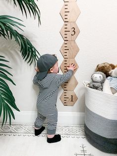 a little boy standing in front of a growth chart with his hands on the wall