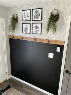 the wall is painted black and has three hanging planters on it, along with two framed pictures