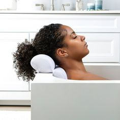 a woman laying in a bathtub with her head resting on the back of it