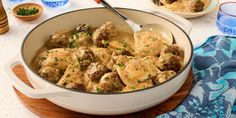 a pot filled with meatballs and gravy on top of a wooden cutting board