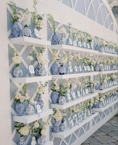 many blue and white vases with flowers on them are lined up against a wall