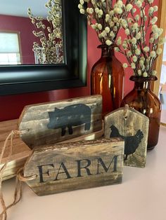 three wooden signs sitting on top of a table next to vases with flowers in them