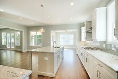 a large kitchen with white cabinets and marble counter tops, along with an island in the middle