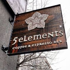 a wooden sign hanging from the side of a building that says, elements coffee and espresso bar