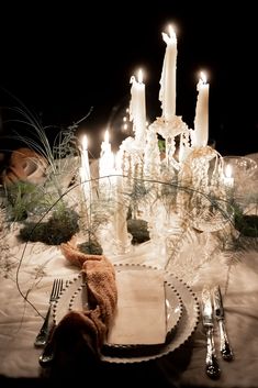 a table set with candles, napkins and silverware