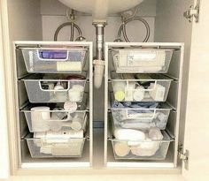 two white baskets are sitting in the bottom half of a cabinet next to a sink