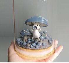 a small figurine in a glass dome with blue and white mushrooms on it