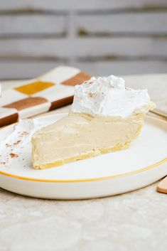 a slice of pie with whipped cream on top sits on a plate next to a fork