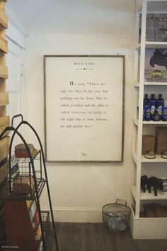 an empty room with shelves filled with bottles and other items on the wall, including a framed poem