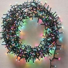 a wreath made out of small lights on a table with a white wall in the background