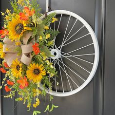 a bicycle wheel wreath with sunflowers and greenery hangs on the front door