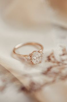 a close up of a gold ring on a white cloth with flowers in the background