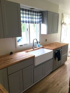 a kitchen with wooden counter tops and gray cabinets in the corner, along with a window