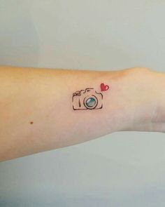 a small camera tattoo on the left wrist and right arm, with a red heart in the center