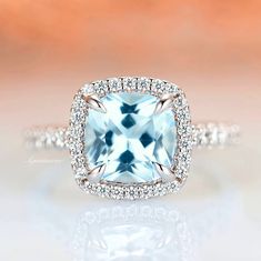 a cushion cut aqua blue topazte surrounded by white diamonds in a halo setting