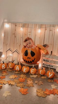 a baby in a pumpkin costume surrounded by fall leaves and lite - up candles