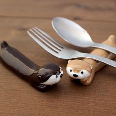 two forks and spoons with animal figurines next to each other on a wooden table