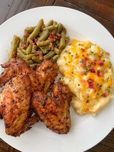 a white plate topped with chicken, mashed potatoes and green beans