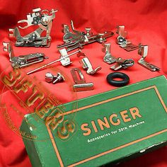 an assortment of sewing tools are on a red cloth with the words singer above it