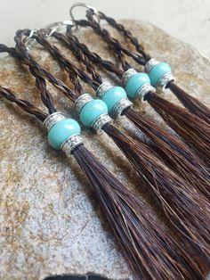 four tassels with turquoise beads are on a rock