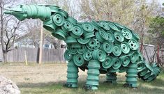 a large green sculpture of a dinosaur made out of rolled up rolls of toilet paper