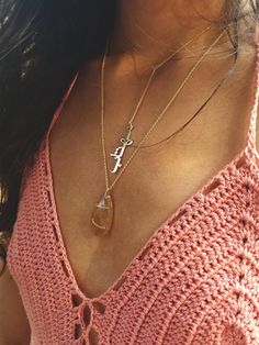 a woman wearing a pink top with a cross pendant on her chest and a chain around her neck