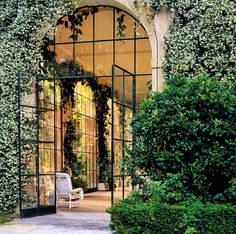 an arch covered in ivy next to a white chair