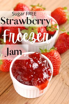 two small white bowls filled with strawberry jam on top of a wooden table next to strawberries