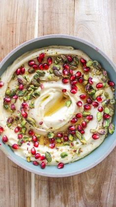 a bowl filled with hummus and pomegranates on top of a wooden table