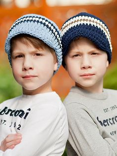 two young boys wearing knitted hats standing next to each other