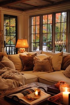 a living room filled with lots of furniture next to two large windows covered in fall leaves