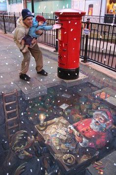 a man and child are looking at a painting on the sidewalk in front of a red phone booth