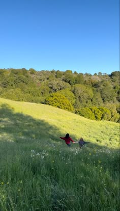 two people are sitting in the grass on a hill