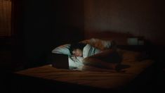 a person laying in bed with a laptop computer on their lap and head resting on the pillow