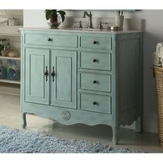 a blue bathroom vanity with two sinks and a rug on the floor in front of it