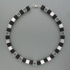 In this special necklace, cubes of real black ebony alternate with nickel silver cubes opened on two sides. The nickel silver cubes align randomly, turning either the closed or the open side of the viewer. This additionally loosens the clear shapes of the necklace. The satin matte ebony cubes complement with the bright silver cubes not only to a contrast between light and dark but also between "nature" and "technology", which makes this necklace a very special piece of jewelry. Dimensions: Lengt Modern Black Necklace With Square Pendant, Modern Black Square Pendant Necklace, Modern Black Square Jewelry, Nature And Technology, Cube Necklace, Special Necklace, Personalized Pendant, Nickel Silver, Delicate Earrings