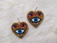 These bead embroidery evil eye heart earrings  would make a perfect and unique gift for family, friend, or yourself ★READY TO SHIP Made with love and care about you!♥ ★DIMENSIONS: 6*4.3 cm (2.36*1.69 Inches) ★The colors can slightly differ from the photo because of photography lighting and monitor settings. ★ESTIMATED SHIPPING TIMES: North America: 2-4 weeks Europe: 1-3 weeks Australia, New Zealand and Oceania: 3-5 weeks Asia Pacific: 2-4 weeks Latin America and the Caribbean: 3-5 weeks North Africa and the Middle East: 3-5 weeks Sub-Saharan Africa: 3-5 weeks ★PLEASE NOTE: I accept payments through Paypal * you no need to have an account* by credit or debit card. 1. Click Check out with PayPal and you'll be redirected to PayPal. Instead of choosing to pay with your PayPal account, select P Beaded Heart Earrings, Heart With Eyes, Heart Evil Eye, Embroidery Red, Earrings Bead, Red Heart Earrings, Beaded Heart, Earrings Heart, Evil Eye Earrings