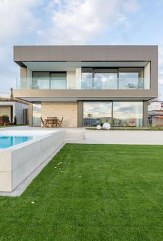 a house with a swimming pool in front of it and grass on the lawn below